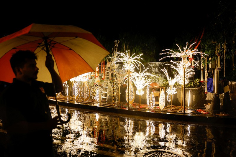 Orang-orang berjalan melewati tempat yang dihiasi lampu menjelang pernikahan putra miliarder Mukesh Ambani, Anant Ambani, dengan Radhika Merchant di Jio World Convention Center di Mumbai, India, Kamis, 11 Juli 2024. (AP Photo/Rafiq Maqbool)