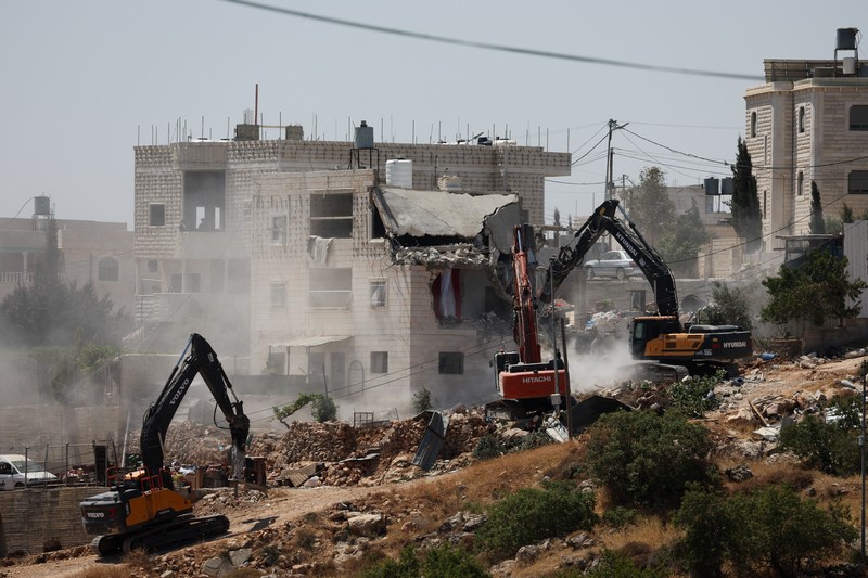 Warga Palesntina menyaksikan penghancuran rumah mereka yang dilakukan oleh militer Israel di Tepi Barat, Kamis (11/7/2024). (REUTERS/Mussa Qawasma)