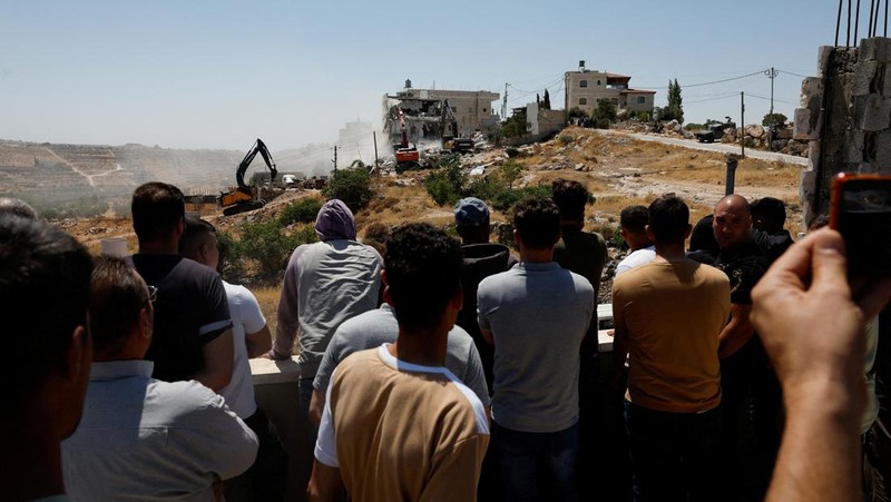Warga Palesntina menyaksikan penghancuran rumah mereka yang dilakukan oleh militer Israel di Tepi Barat, Kamis (11/7/2024). (REUTERS/Mussa Qawasma)