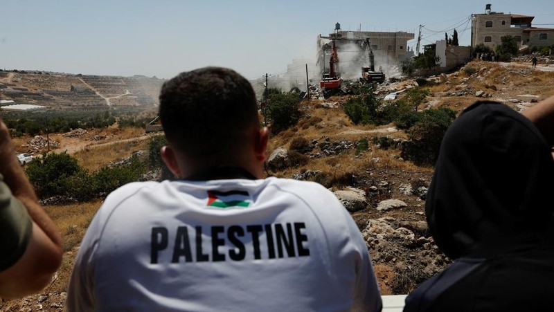 Warga Palesntina menyaksikan penghancuran rumah mereka yang dilakukan oleh militer Israel di Tepi Barat, Kamis (11/7/2024). (REUTERS/Mussa Qawasma)