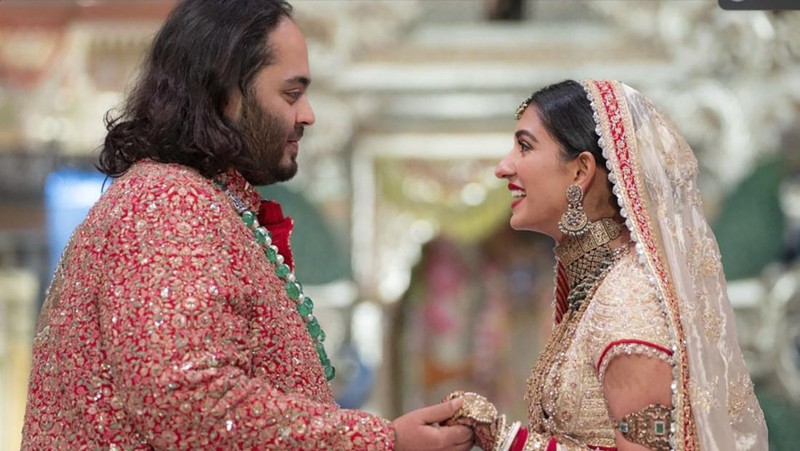 Miliarder Mukesh Ambani, tengah, menggandeng tangan putranya Anant Ambani saat mereka berjalan bersama Nita Ambani, kanan, di pernikahan Anant dan Radhika Merchant di Jio World Convention Center di Mumbai, India, Jumat, 12 Juli 2024. (AP Photo /Rajanish Kakade)