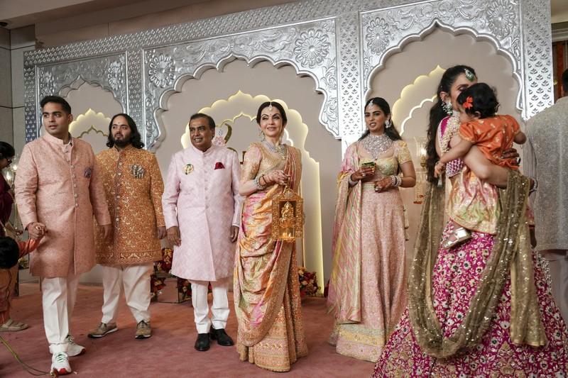 Miliarder Mukesh Ambani, tengah, menggandeng tangan putranya Anant Ambani saat mereka berjalan bersama Nita Ambani, kanan, di pernikahan Anant dan Radhika Merchant di Jio World Convention Center di Mumbai, India, Jumat, 12 Juli 2024. (AP Photo /Rajanish Kakade)