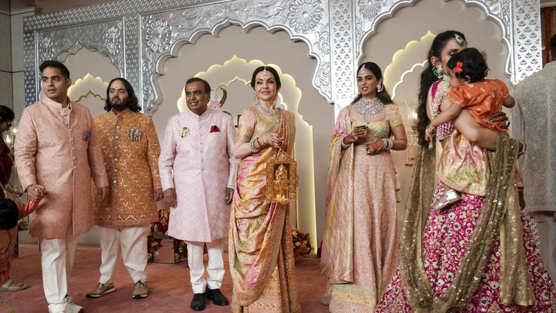 Miliarder Mukesh Ambani, tengah, menggandeng tangan putranya Anant Ambani saat mereka berjalan bersama Nita Ambani, kanan, di pernikahan Anant dan Radhika Merchant di Jio World Convention Center di Mumbai, India, Jumat, 12 Juli 2024. (AP Photo /Rajanish Kakade)