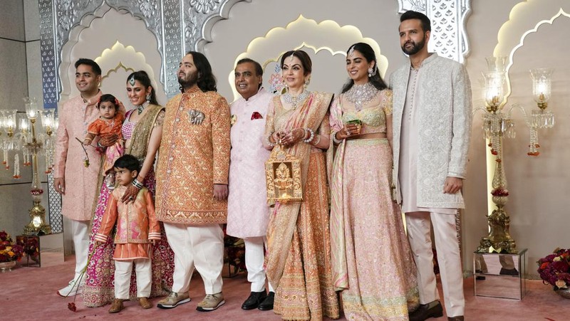 Miliarder Mukesh Ambani, tengah, menggandeng tangan putranya Anant Ambani saat mereka berjalan bersama Nita Ambani, kanan, di pernikahan Anant dan Radhika Merchant di Jio World Convention Center di Mumbai, India, Jumat, 12 Juli 2024. (AP Photo /Rajanish Kakade)
