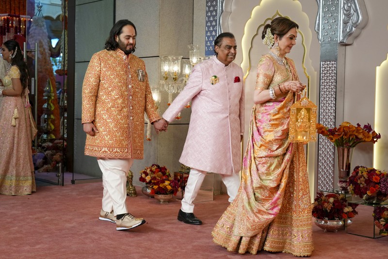 Miliarder Mukesh Ambani, tengah, menggandeng tangan putranya Anant Ambani saat mereka berjalan bersama Nita Ambani, kanan, di pernikahan Anant dan Radhika Merchant di Jio World Convention Center di Mumbai, India, Jumat, 12 Juli 2024. (AP Photo /Rajanish Kakade)