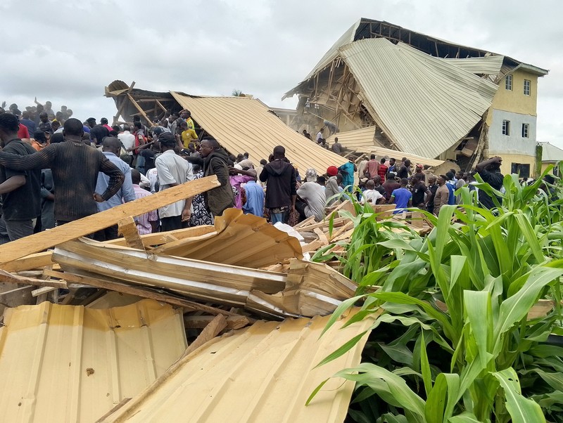 Orang-orang berdiri di dekat reruntuhan gedung sekolah milik Saint Academy yang runtuh di komunitas Busa Buji, negara bagian Plateau, Nigeria 12 Juli 2024. Orang-orang berdiri di dekat reruntuhan gedung sekolah milik Saint Academy yang runtuh di komunitas Busa Buji, negara bagian Plateau, Nigeria 12 Juli 2024. (REUTERS/Joshua Inusa)