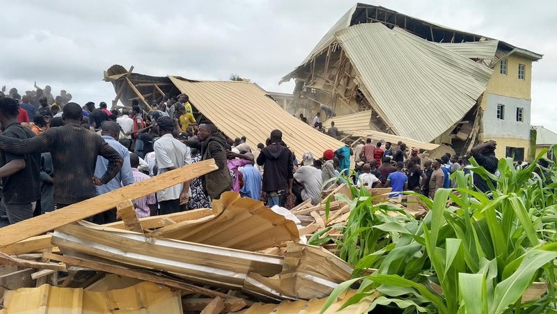 Orang-orang berdiri di dekat reruntuhan gedung sekolah milik Saint Academy yang runtuh di komunitas Busa Buji, negara bagian Plateau, Nigeria 12 Juli 2024. (REUTERS/Joshua Inusa)