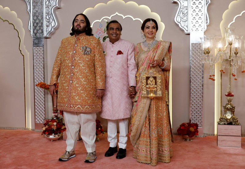 Miliarder Mukesh Ambani, tengah, menggandeng tangan putranya Anant Ambani saat mereka berjalan bersama Nita Ambani, kanan, di pernikahan Anant dan Radhika Merchant di Jio World Convention Center di Mumbai, India, Jumat, 12 Juli 2024. (AP Photo /Rajanish Kakade)