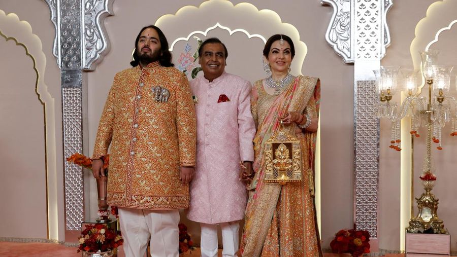 Miliarder Mukesh Ambani, tengah, menggandeng tangan putranya Anant Ambani saat mereka berjalan bersama Nita Ambani, kanan, di pernikahan Anant dan Radhika Merchant di Jio World Convention Center di Mumbai, India, Jumat, 12 Juli 2024. (AP Photo /Rajanish Kakade)