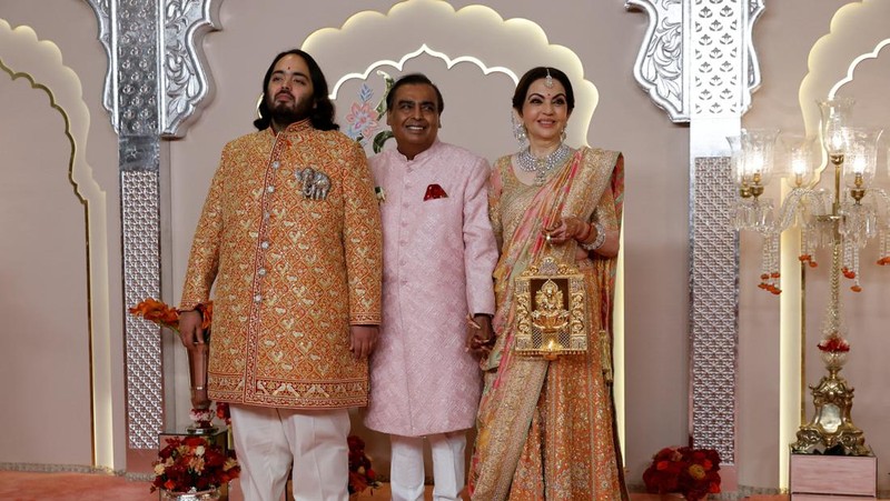 Miliarder Mukesh Ambani, tengah, menggandeng tangan putranya Anant Ambani saat mereka berjalan bersama Nita Ambani, kanan, di pernikahan Anant dan Radhika Merchant di Jio World Convention Center di Mumbai, India, Jumat, 12 Juli 2024. (AP Photo /Rajanish Kakade)