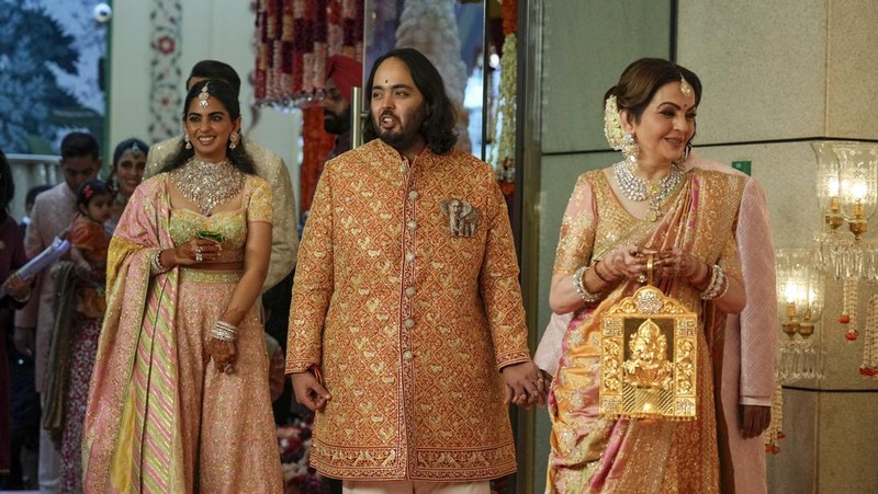 Miliarder Mukesh Ambani, tengah, menggandeng tangan putranya Anant Ambani saat mereka berjalan bersama Nita Ambani, kanan, di pernikahan Anant dan Radhika Merchant di Jio World Convention Center di Mumbai, India, Jumat, 12 Juli 2024. (AP Photo /Rajanish Kakade)