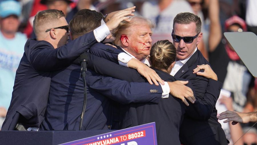 Republican presidential candidate former President Donald Trump is helped off the stage at a campaign event in Butler, Pa., on Saturday, July 13, 2024. (AP Photo/Gene J. Puskar)