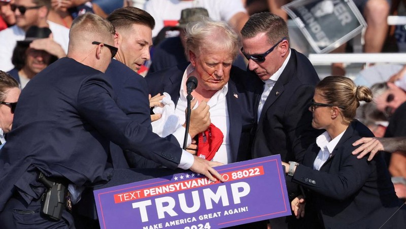 Kandidat presiden dari Partai Republik dan mantan Presiden AS Donald Trump dibantu oleh petugas keamanan setelah terdengar suara tembakan saat kampanye di Butler Farm Show di Butler, Pennsylvania, AS, 13 Juli 2024. (REUTERS/Brendan McDermid)