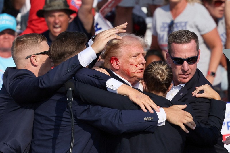 Kandidat presiden dari Partai Republik dan mantan Presiden AS Donald Trump dibantu oleh petugas keamanan setelah terdengar suara tembakan saat kampanye di Butler Farm Show di Butler, Pennsylvania, AS, 13 Juli 2024. (REUTERS/Brendan McDermid)