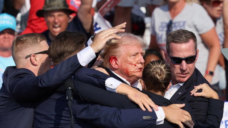 Kandidat presiden dari Partai Republik dan mantan Presiden AS Donald Trump dibantu oleh petugas keamanan setelah terdengar suara tembakan saat kampanye di Butler Farm Show di Butler, Pennsylvania, AS, 13 Juli 2024. (REUTERS/Brendan McDermid)