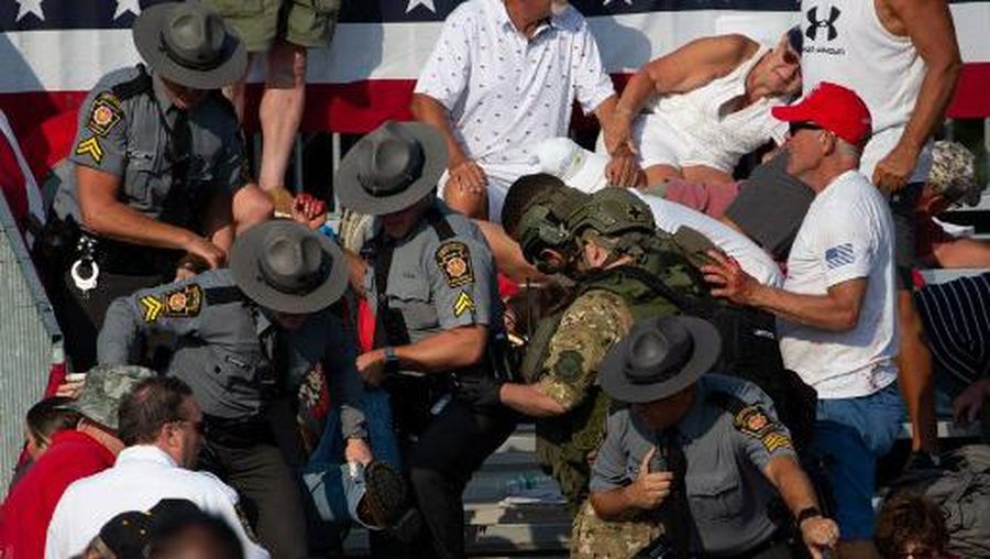 A person is removed by state police from the stands after guns were fired at Republican candidate Donald Trump at a campaign event at Butler Farm Show Inc. in Butler, Pennsylvania, July 13, 2024. The suspected shooter who wounded Republican presidential candidate Donald Trump at a rally is dead, US media reported Saturday, along with one bystander. (Photo by Rebecca DROKE / AFP)
