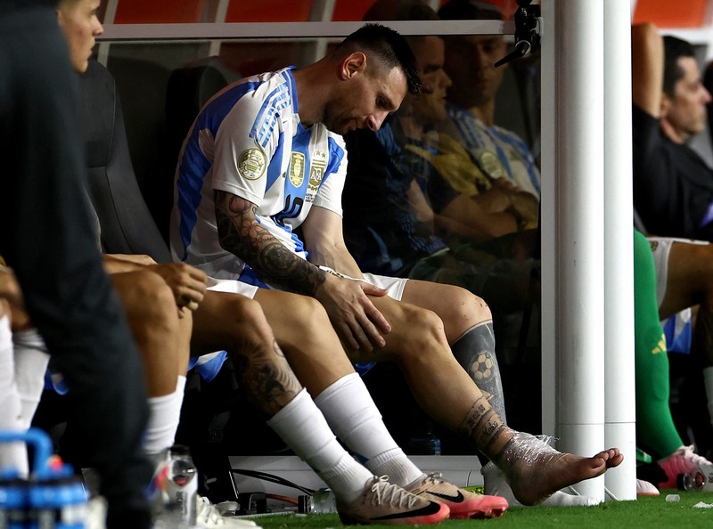 Pemain Argentina Lionel Messi duduk di bangku cadangan setelah meninggalkan lapangan karena cedera saat pertandingan sepak bola final Copa America melawan Kolombia di Miami Gardens, Fl., Minggu, 14 Juli 2024. (AP Photo/Julio Cortez)