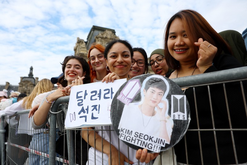 Jin, anggota tertua supergrup K-pop BTS, membawa obor Olimpiade, Minggu, 14 Juli 2024 di Paris. (AP Photo/Louise Delmotte)
