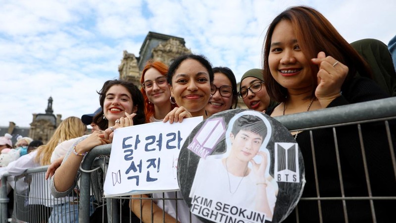 Jin, anggota tertua supergrup K-pop BTS, membawa obor Olimpiade, Minggu, 14 Juli 2024 di Paris. (AP Photo/Louise Delmotte)