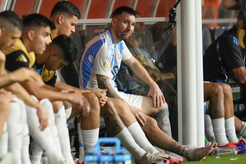Pemain Argentina Lionel Messi duduk di bangku cadangan setelah meninggalkan lapangan karena cedera saat pertandingan sepak bola final Copa America melawan Kolombia di Miami Gardens, Fl., Minggu, 14 Juli 2024. (AP Photo/Julio Cortez)