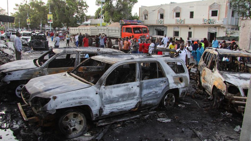 Orang-orang berkumpul di dekat puing-puing kendaraan yang hancur di lokasi ledakan di luar sebuah restoran tempat pengunjung menonton final turnamen sepak bola Euro 2024 di TV, di distrik Bondhere, Mogadishu, Somalia, 15 Juli 2024. (REUTERS/Feisal Omar)