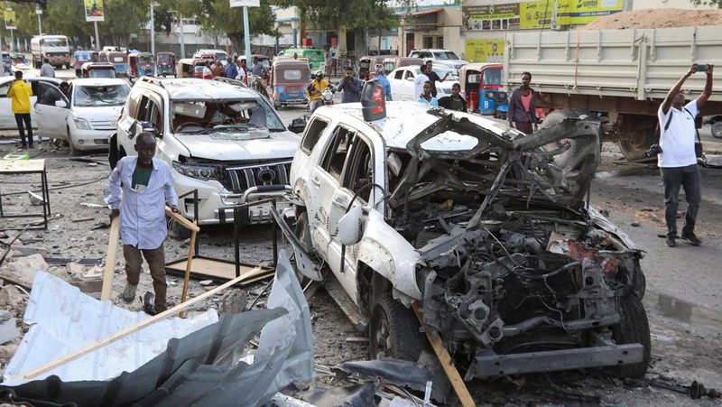 Orang-orang berkumpul di dekat puing-puing kendaraan yang hancur di lokasi ledakan di luar sebuah restoran tempat pengunjung menonton final turnamen sepak bola Euro 2024 di TV, di distrik Bondhere, Mogadishu, Somalia, 15 Juli 2024. (REUTERS/Feisal Omar)