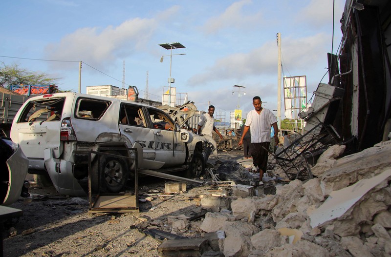 Orang-orang berkumpul di dekat puing-puing kendaraan yang hancur di lokasi ledakan di luar sebuah restoran tempat pengunjung menonton final turnamen sepak bola Euro 2024 di TV, di distrik Bondhere, Mogadishu, Somalia, 15 Juli 2024. (REUTERS/Feisal Omar)