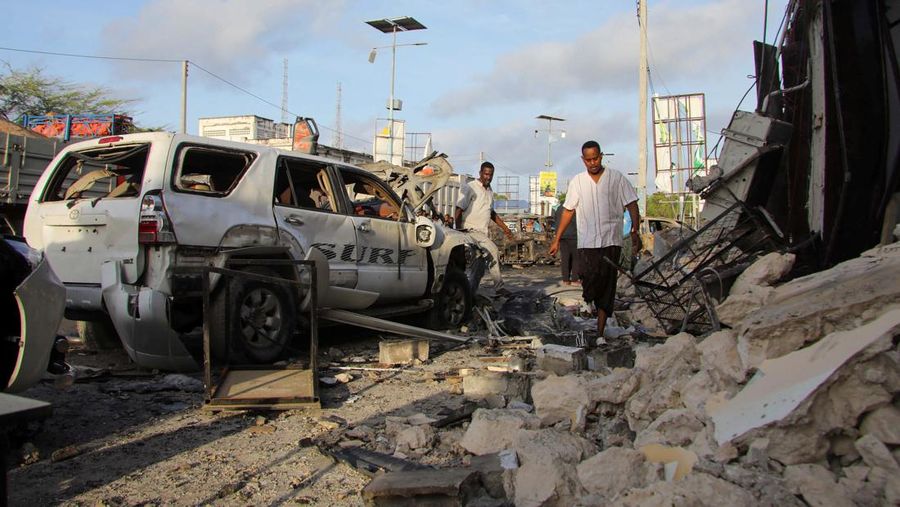 Orang-orang berkumpul di dekat puing-puing kendaraan yang hancur di lokasi ledakan di luar sebuah restoran tempat pengunjung menonton final turnamen sepak bola Euro 2024 di TV, di distrik Bondhere, Mogadishu, Somalia, 15 Juli 2024. (REUTERS/Feisal Omar)
