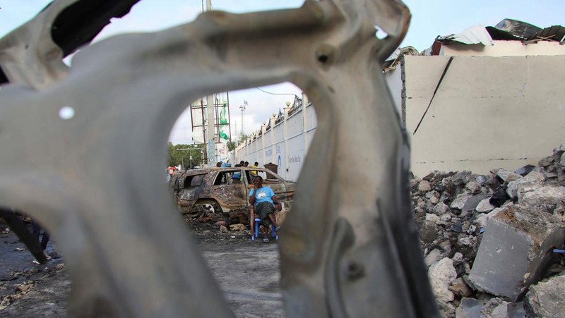 Orang-orang berkumpul di dekat puing-puing kendaraan yang hancur di lokasi ledakan di luar sebuah restoran tempat pengunjung menonton final turnamen sepak bola Euro 2024 di TV, di distrik Bondhere, Mogadishu, Somalia, 15 Juli 2024. (REUTERS/Feisal Omar)