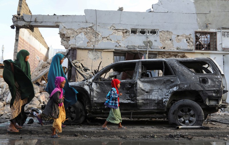 Orang-orang berkumpul di dekat puing-puing kendaraan yang hancur di lokasi ledakan di luar sebuah restoran tempat pengunjung menonton final turnamen sepak bola Euro 2024 di TV, di distrik Bondhere, Mogadishu, Somalia, 15 Juli 2024. (REUTERS/Feisal Omar)