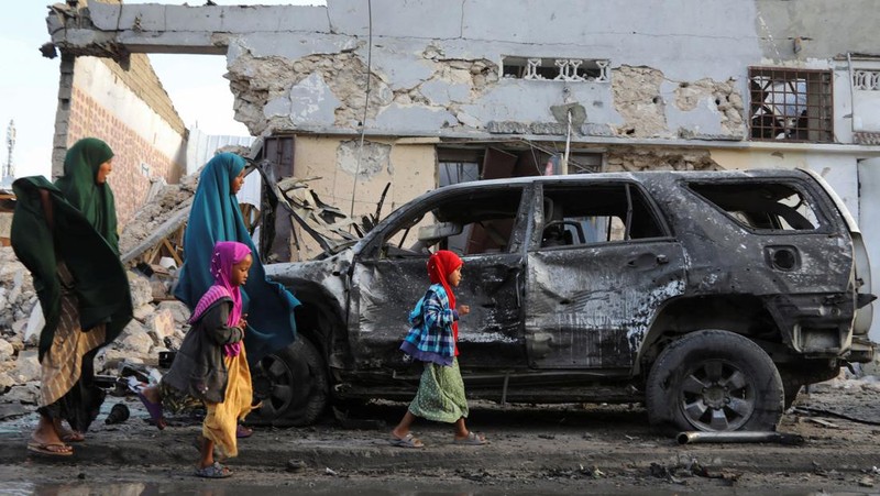 Orang-orang berkumpul di dekat puing-puing kendaraan yang hancur di lokasi ledakan di luar sebuah restoran tempat pengunjung menonton final turnamen sepak bola Euro 2024 di TV, di distrik Bondhere, Mogadishu, Somalia, 15 Juli 2024. (REUTERS/Feisal Omar)