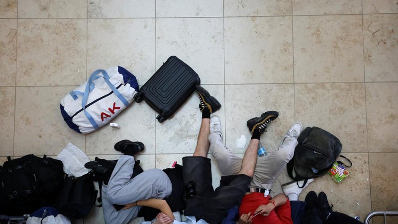 Seorang anak laki-laki tertidur di lantai saat para pelancong mengantri di Bandara Internasional Brussels di Brussels, Jumat, 19 Juli 2024. Pemadaman teknologi global membuat penerbangan terhenti, membuat bank dan sistem rumah sakit offline, dan outlet media tidak mengudara pada hari Jumat secara besar-besaran. (AP/Harry Nakos)