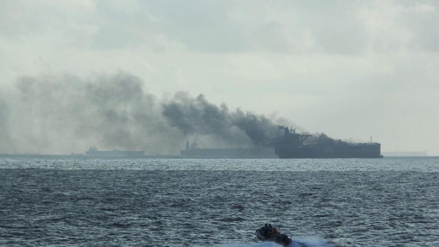 Perahu karet RSS Supreme dengan lambung kaku di sekitar kapal yang terbakar menyusul kebakaran di dua kapal tanker minyak sekitar 55 km (34 mil) timur laut pulau Pedra Branca di Singapura, 19 Juli 2024. (via REUTERS/Republic of Singapore Navy)