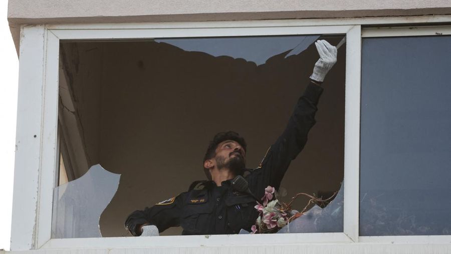 Personel darurat Israel memeriksa puing-puing di dekat apartemen di Tel Aviv yang dihantam serangan drone Houthi. (AP Photo/Oded Balilty)