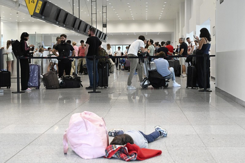 Seorang anak laki-laki tertidur di lantai saat para pelancong mengantri di Bandara Internasional Brussels di Brussels, Jumat, 19 Juli 2024. Pemadaman teknologi global membuat penerbangan terhenti, membuat bank dan sistem rumah sakit offline, dan outlet media tidak mengudara pada hari Jumat secara besar-besaran. (AP/Harry Nakos)