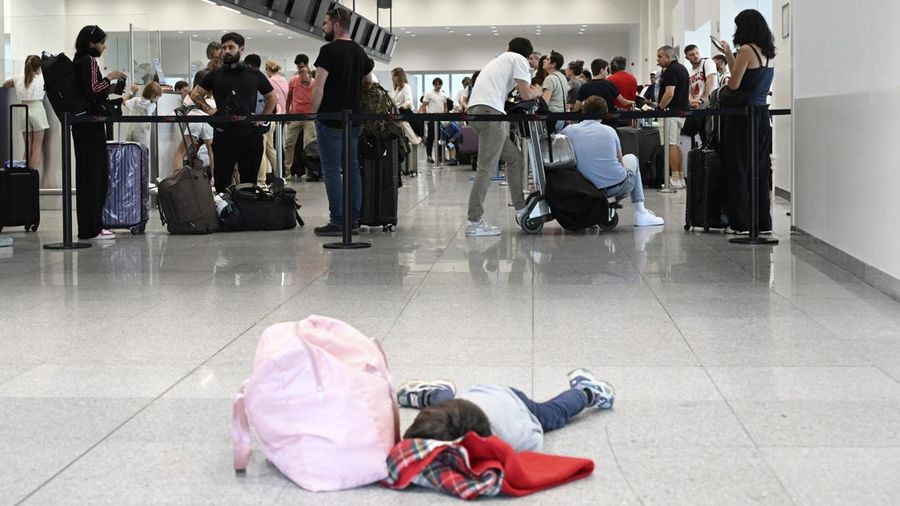 Seorang anak laki-laki tertidur di lantai saat para pelancong mengantri di Bandara Internasional Brussels di Brussels, Jumat, 19 Juli 2024. Pemadaman teknologi global membuat penerbangan terhenti, membuat bank dan sistem rumah sakit offline, dan outlet media tidak mengudara pada hari Jumat secara besar-besaran. (AP/Harry Nakos)