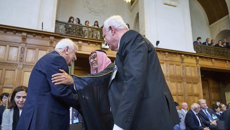 Penasihat kebijakan luar negeri Palestina Riad Malki bertemu dengan salah satu anggota tim Israel sebelum hakim memasuki Mahkamah Internasional, atau Pengadilan Dunia, di Den Haag, Belanda, Jumat 19 Juli 2024. (AP/Phil Nijhuis)