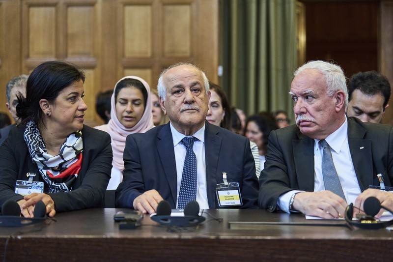 Penasihat kebijakan luar negeri Palestina Riad Malki bertemu dengan salah satu anggota tim Israel sebelum hakim memasuki Mahkamah Internasional, atau Pengadilan Dunia, di Den Haag, Belanda, Jumat 19 Juli 2024. (AP/Phil Nijhuis)