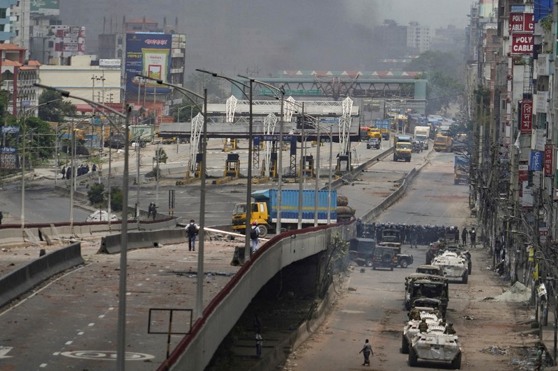 Petugas keamanan berjalan melewati kendaraan organisasi milik pemerintah yang rusak, yang dibakar oleh massa selama bentrokan setelah kekerasan meletus menyusul protes mahasiswa terhadap kuota pekerjaan pemerintah, di Dhaka, Bangladesh, 22 Juli 2024. Petugas keamanan berjalan melewati kendaraan organisasi milik pemerintah yang rusak, yang dibakar oleh massa selama bentrokan setelah kekerasan meletus menyusul protes mahasiswa terhadap kuota pekerjaan pemerintah, di Dhaka, Bangladesh, 22 Juli 2024. (REUTERS/Mohammad Ponir Hossain)