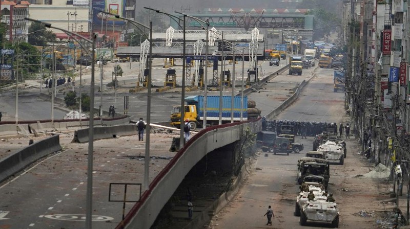 Petugas keamanan berjalan melewati kendaraan organisasi milik pemerintah yang rusak, yang dibakar oleh massa selama bentrokan setelah kekerasan meletus menyusul protes mahasiswa terhadap kuota pekerjaan pemerintah, di Dhaka, Bangladesh, 22 Juli 2024. (REUTERS/Mohammad Ponir Hossain)