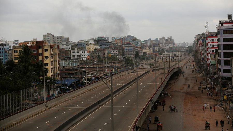 Petugas keamanan berjalan melewati kendaraan organisasi milik pemerintah yang rusak, yang dibakar oleh massa selama bentrokan setelah kekerasan meletus menyusul protes mahasiswa terhadap kuota pekerjaan pemerintah, di Dhaka, Bangladesh, 22 Juli 2024. (REUTERS/Mohammad Ponir Hossain)