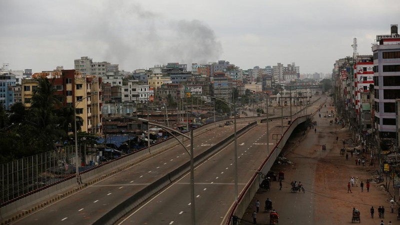 Petugas keamanan berjalan melewati kendaraan organisasi milik pemerintah yang rusak, yang dibakar oleh massa selama bentrokan setelah kekerasan meletus menyusul protes mahasiswa terhadap kuota pekerjaan pemerintah, di Dhaka, Bangladesh, 22 Juli 2024. (REUTERS/Mohammad Ponir Hossain)