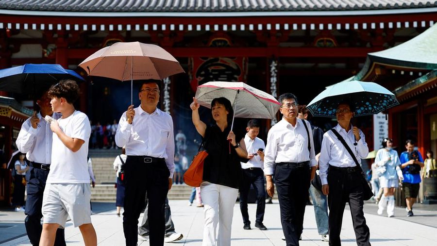 Pejalan kaki yang memegang payung berjalan di bawah sinar matahari yang terik di kuil Sensoji saat pemerintah Jepang mengeluarkan peringatan serangan panas di 39 dari 47 prefektur di Tokyo, Jepang, 22 Juli 2024. (REUTERS/Issei Kato)
