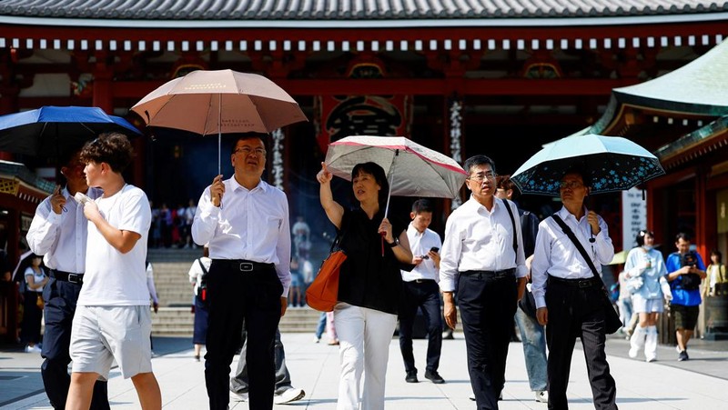 Pejalan kaki yang memegang payung berjalan di bawah sinar matahari yang terik di kuil Sensoji saat pemerintah Jepang mengeluarkan peringatan serangan panas di 39 dari 47 prefektur di Tokyo, Jepang, 22 Juli 2024. (REUTERS/Issei Kato)