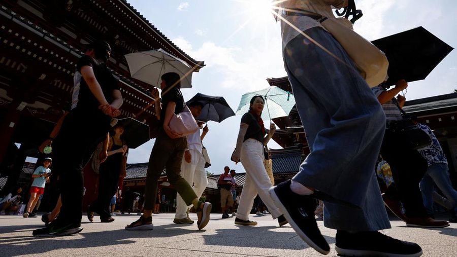 Pejalan kaki yang memegang payung berjalan di bawah sinar matahari yang terik di kuil Sensoji saat pemerintah Jepang mengeluarkan peringatan serangan panas di 39 dari 47 prefektur di Tokyo, Jepang, 22 Juli 2024. (REUTERS/Issei Kato)