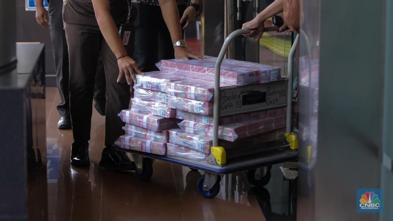 Petugas kejakasaan memindahkan uang barang bukti terkait kasus korupsi IUP PT Timah di Kejaksaan Negeri Jakarta Selatan, Senin (22/7/2024). (CNBC Indonesia/Faisal Rahman)
