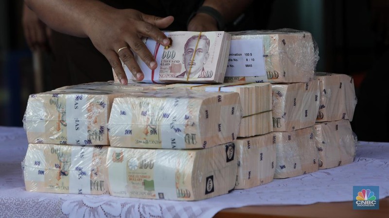 Petugas kejakasaan memindahkan uang barang bukti terkait kasus korupsi IUP PT Timah di Kejaksaan Negeri Jakarta Selatan, Senin (22/7/2024). (CNBC Indonesia/Faisal Rahman)