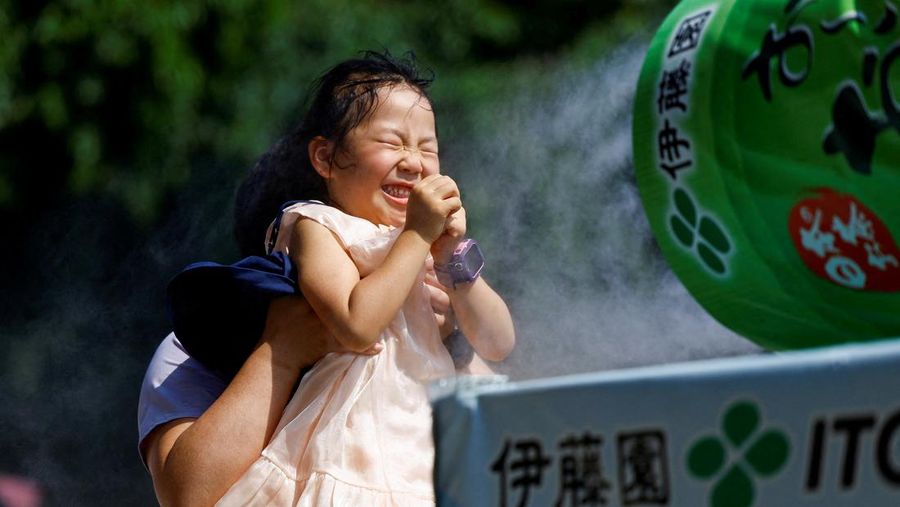 Seorang anak bereaksi ketika sebuah keluarga beristirahat di samping kabut dingin di kuil Sensoji ketika pemerintah Jepang mengeluarkan peringatan serangan panas di 39 dari 47 prefektur di Tokyo, Jepang, 22 Juli 2024. (REUTERS/Issei Kato)