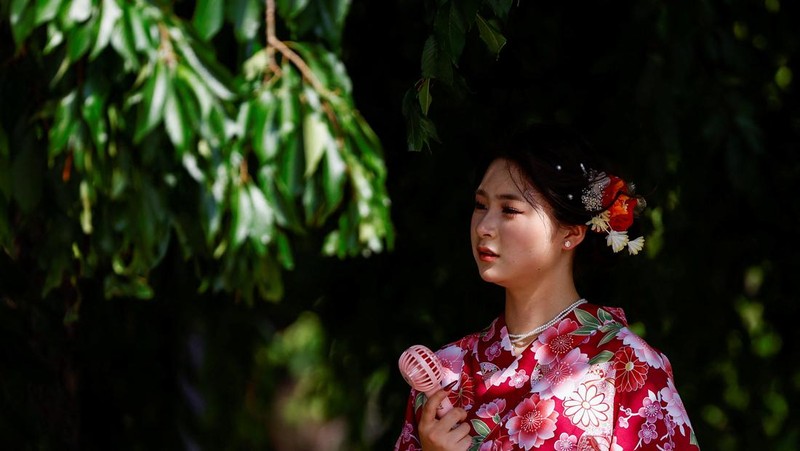 Pejalan kaki yang memegang payung berjalan di bawah sinar matahari yang terik di kuil Sensoji saat pemerintah Jepang mengeluarkan peringatan serangan panas di 39 dari 47 prefektur di Tokyo, Jepang, 22 Juli 2024. (REUTERS/Issei Kato)