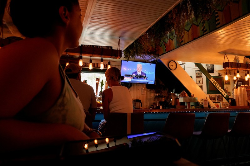 People at a restaurant called Somewhere look at a TV where U.S. President Joe Biden can be seen, on the day he announced he is stopping his bid for reelection, in Rehoboth Beach, Delaware, U.S., July 21, 2024. REUTERS/Ken Cedeno